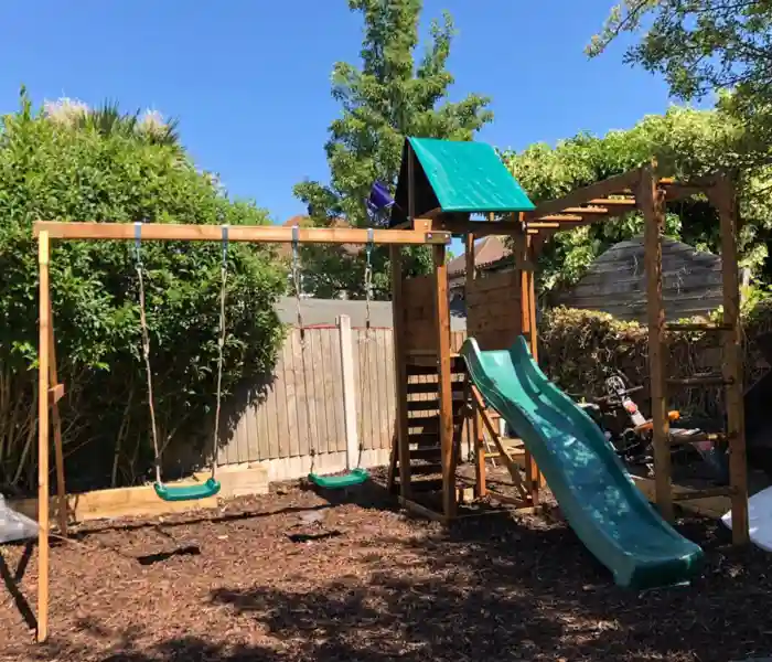 Large wooden children's climbing frame and slide assembled in a North London garden