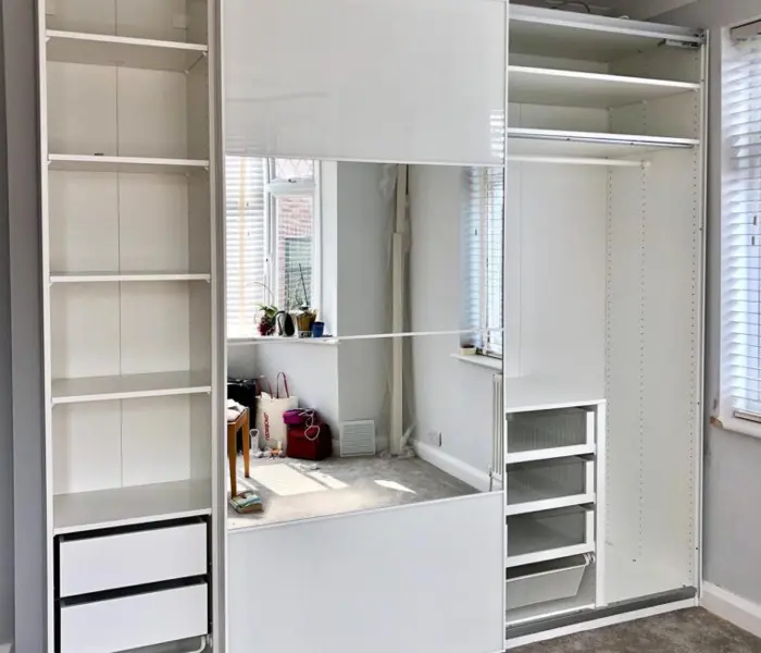 Three-door IKEA PAX wardrobe built and anchored to the wall in a London bedroom